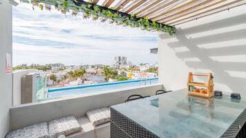 A balcony with a view of a cityscape and a swimming pool.