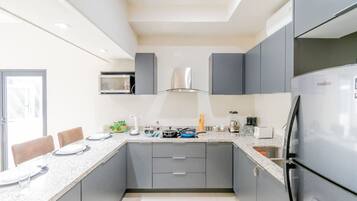 A modern kitchen with grey cabinets, a stainless steel refrigerator, and a microwave above the stove.