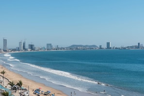 Paisatge urbà costaner amb platja, cel serè i edificis alts.