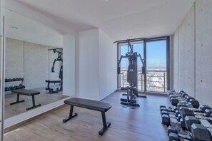 Un gimnasio con bancos, mancuernas y máquinas de pesas.