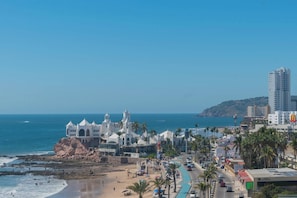 Un paysage urbain côtier avec une plage, un bâtiment blanc ressemblant à une église et un grand hôtel.