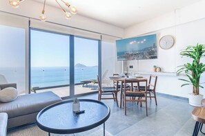 A modern living room with a large window, a dining area, and a flat-screen TV.