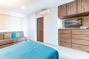 A bedroom with a bed, a sofa, a wardrobe, and a television.
