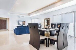 Un'area pranzo moderna con un tavolo rotondo, sedie e un divano blu in una stanza luminosa con ampie finestre.