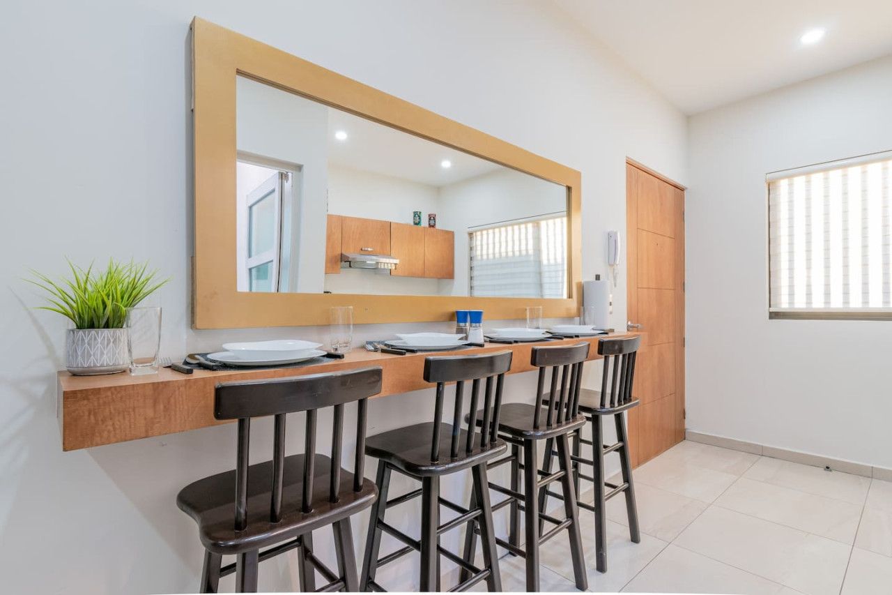 A modern kitchen with a large mirror, wooden cabinets, and a dining area with four chairs.