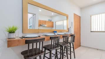 A modern kitchen with a large mirror, wooden cabinets, and a dining area with four chairs.