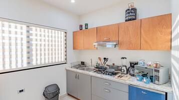 A compact kitchen with grey cabinets, a stainless steel sink, and a coffee machine.