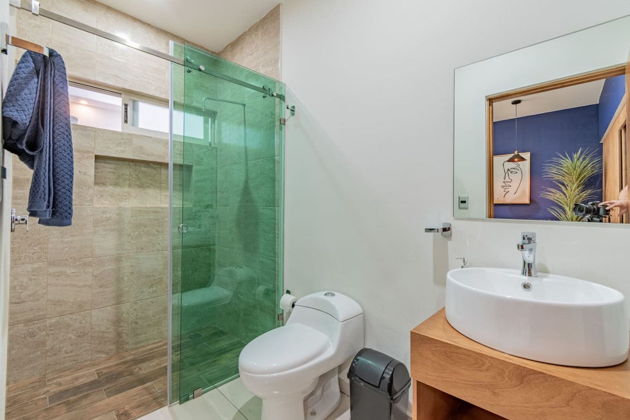 A modern bathroom with a glass-enclosed shower, a white toilet, and a wooden vanity with a white sink.