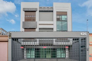 Un edificio con entrada porticada, el número '426' en la fachada y un cielo despejado al fondo.