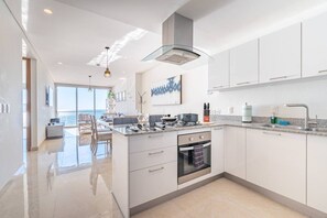A modern kitchen with a central island, stainless steel appliances, and a view to the outside.