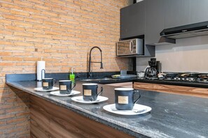 A modern kitchen with a brick wall, a stainless steel microwave, and a gas stove.