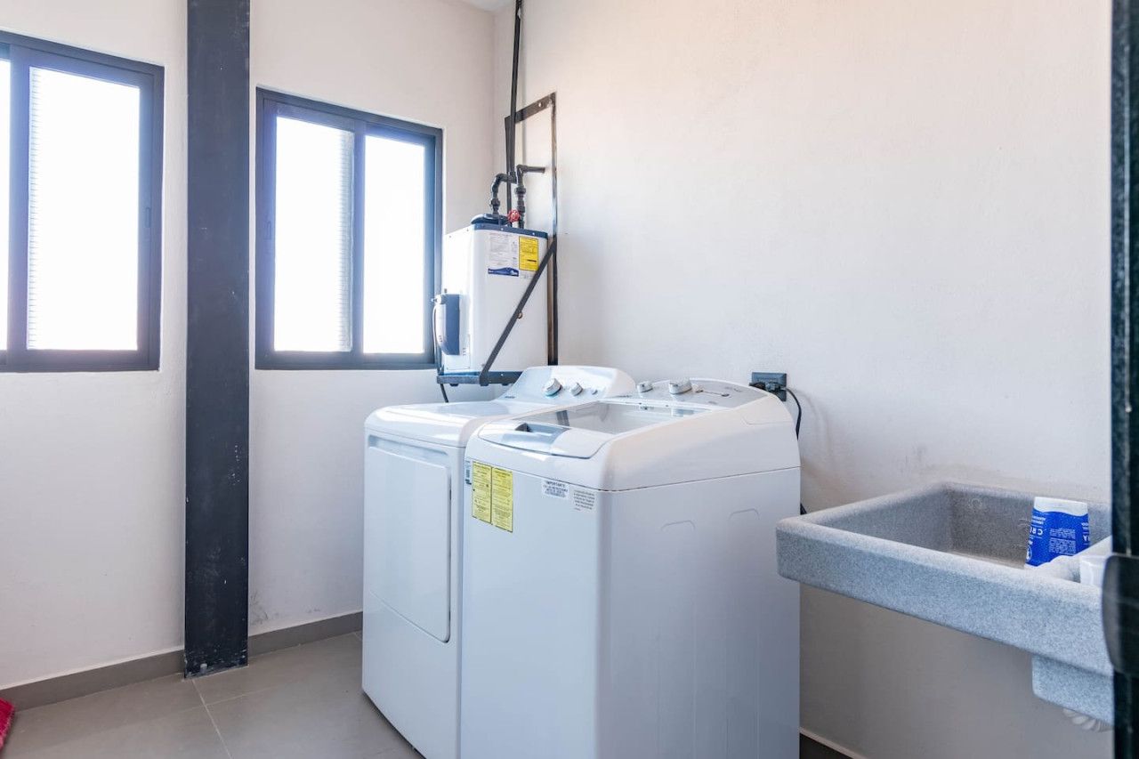 A laundry room with two front-loading washing machines, a water heater, and a utility sink.