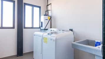 A laundry room with two front-loading washing machines, a water heater, and a utility sink.