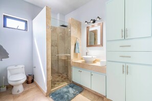 Une salle de bain équipée de toilettes, d’une douche, d’un lavabo et de meubles de rangement.