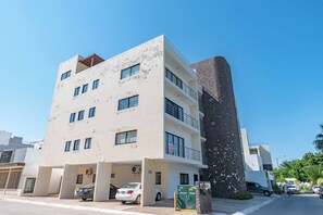 Un immeuble à plusieurs étages doté d’un espace de stationnement, d’une enseigne et d’une structure adjacente de grande hauteur.