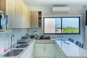 A modern kitchen with granite countertops, stainless steel sinks, and a large window offering a city view. - Depa Amplio, Comodo, y Privado en Zona turistica (Mazatlán)