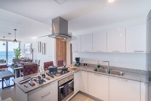 Cocina moderna con una isla central, electrodomésticos de acero inoxidable y un amplio ventanal con vistas al mar.