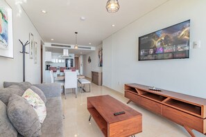 A modern living room with a sofa, coffee table, and TV wall art.