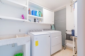A laundry area with a washing machine, dryer, and a shelf with cleaning supplies.