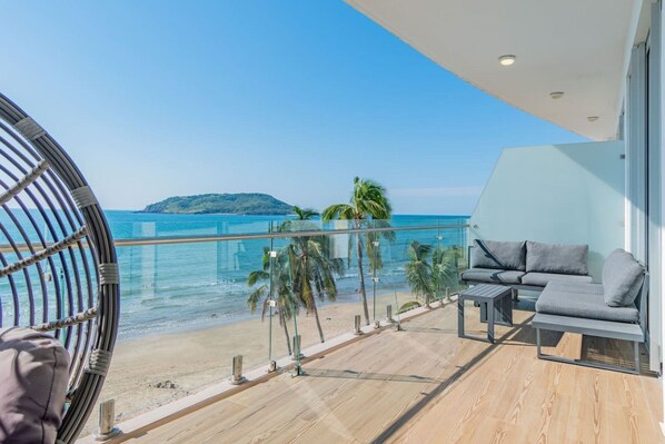 A balcony with a view of the beach and ocean, furnished with a sofa and a table.