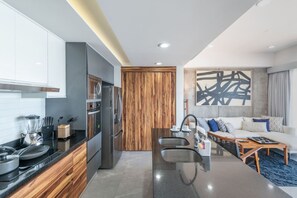 A modern kitchen with a central island, built-in appliances, and a wooden accent wall. - Vista Espectacular en Depa Sobre Malecon (Mazatlán)