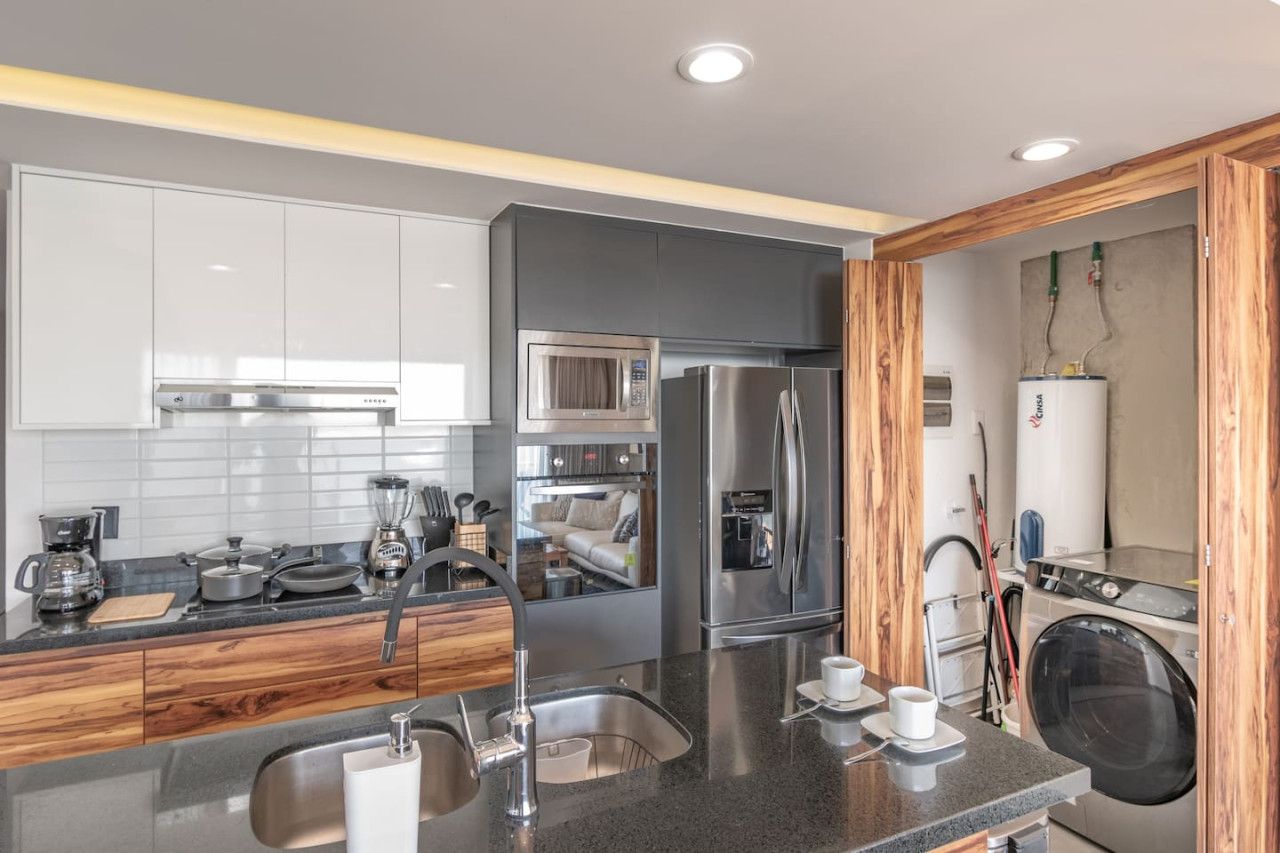 Una cocina moderna con electrodomésticos de acero inoxidable, horno empotrado y cafetera.