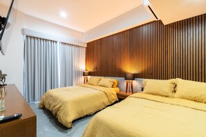 Habitación de hotel con dos camas, un panel de pared de listones de madera, un escritorio con control remoto y una cortina.