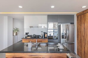 A modern kitchen with a central island, stainless steel appliances, and wooden cabinetry.