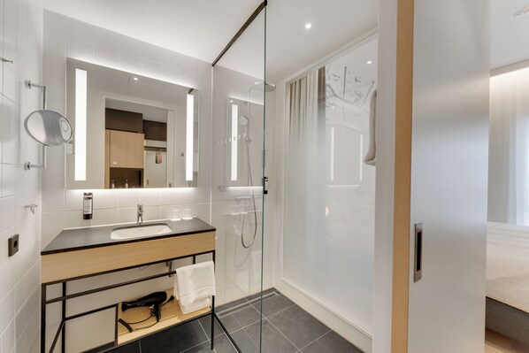 A modern bathroom with a glass-enclosed shower, a wooden vanity, and a large mirror.