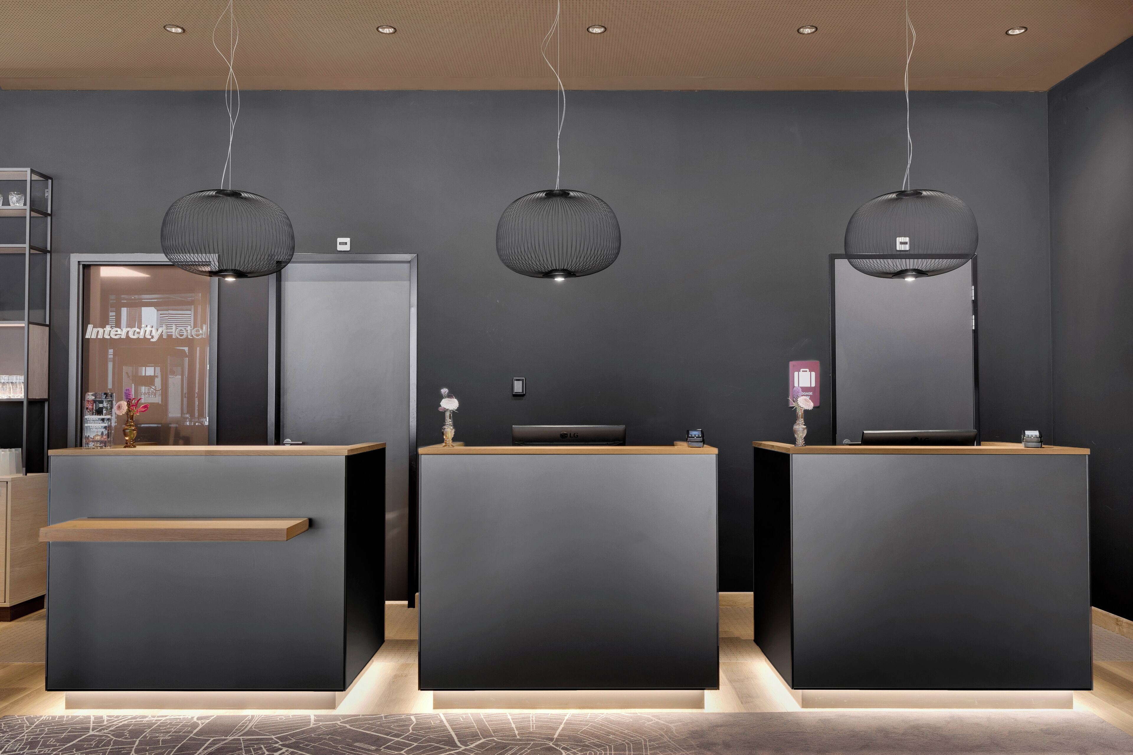 Un área de recepción con tres mostradores oscuros, cada uno con una encimera de madera y un televisor de pantalla plana.