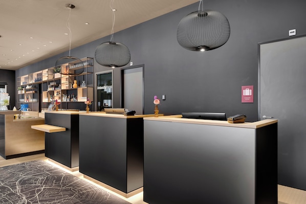 A modern reception desk with a minimalist design, a bar area with shelves of bottles, and a "Lobby" sign.