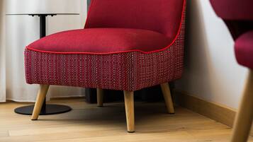 Una silla roja con asiento de mimbre y patas de madera en una habitación con suelo de madera y una mesa negra.