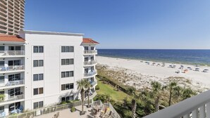 Een strandhotel met meerdere balkons met uitzicht op het strand en de oceaan.
