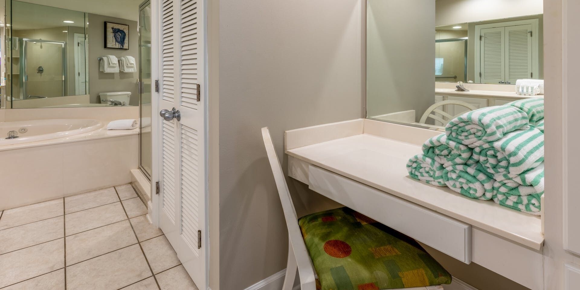 Un baño con bañera, ducha, inodoro y lavamanos. Hay un perchero con toallas y un tapete de baño verde con estampado.
