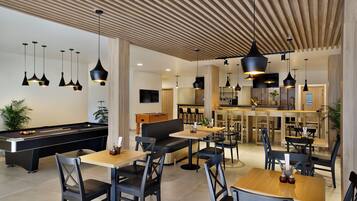 A modern lounge area with pool tables, sofas, and dining tables.