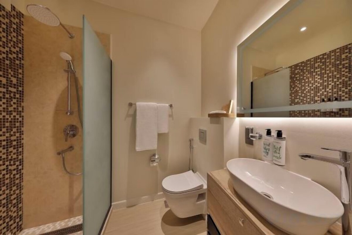A modern bathroom with a shower, toilet, and sink.
