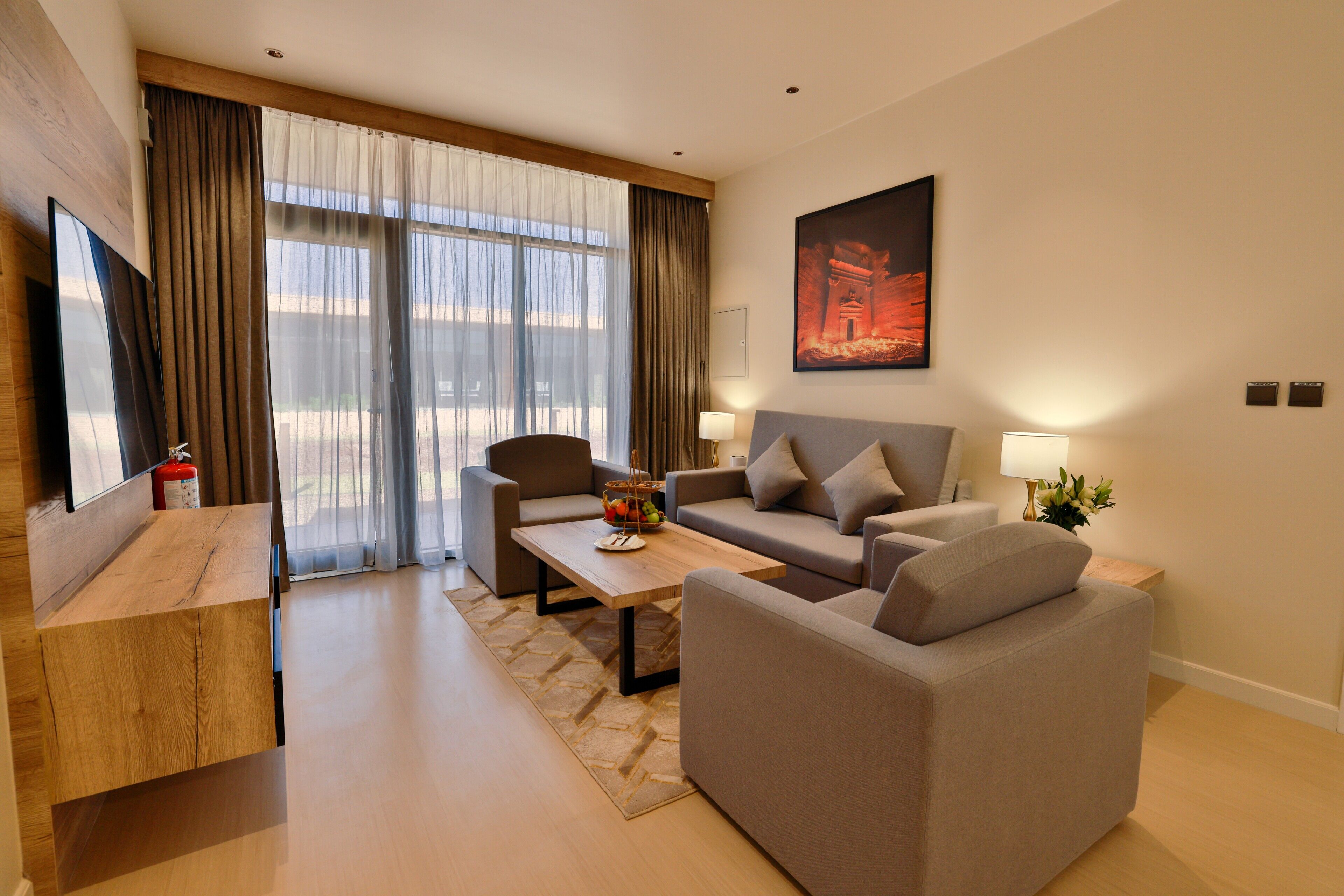 Een moderne woonkamer met een bank, fauteuil, salontafel en een flatscreen televisie.