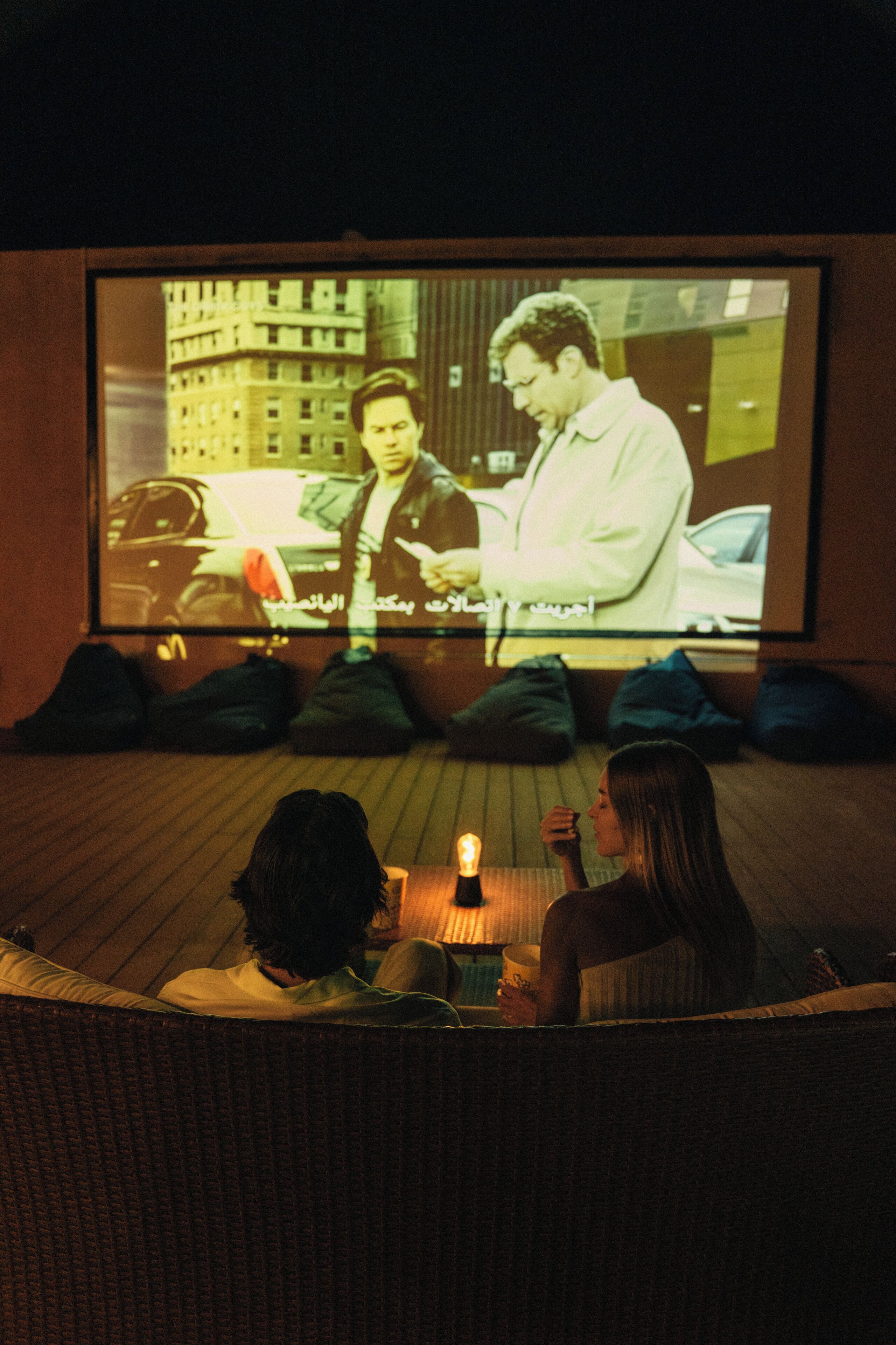 A cinema room with a large screen, seating, and a candle on the floor.