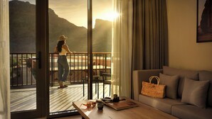 A room with a balcony, a sofa, a table with a handbag, and a view of mountains. - Cloud 7 Residence AlUla (Al-'Ula)