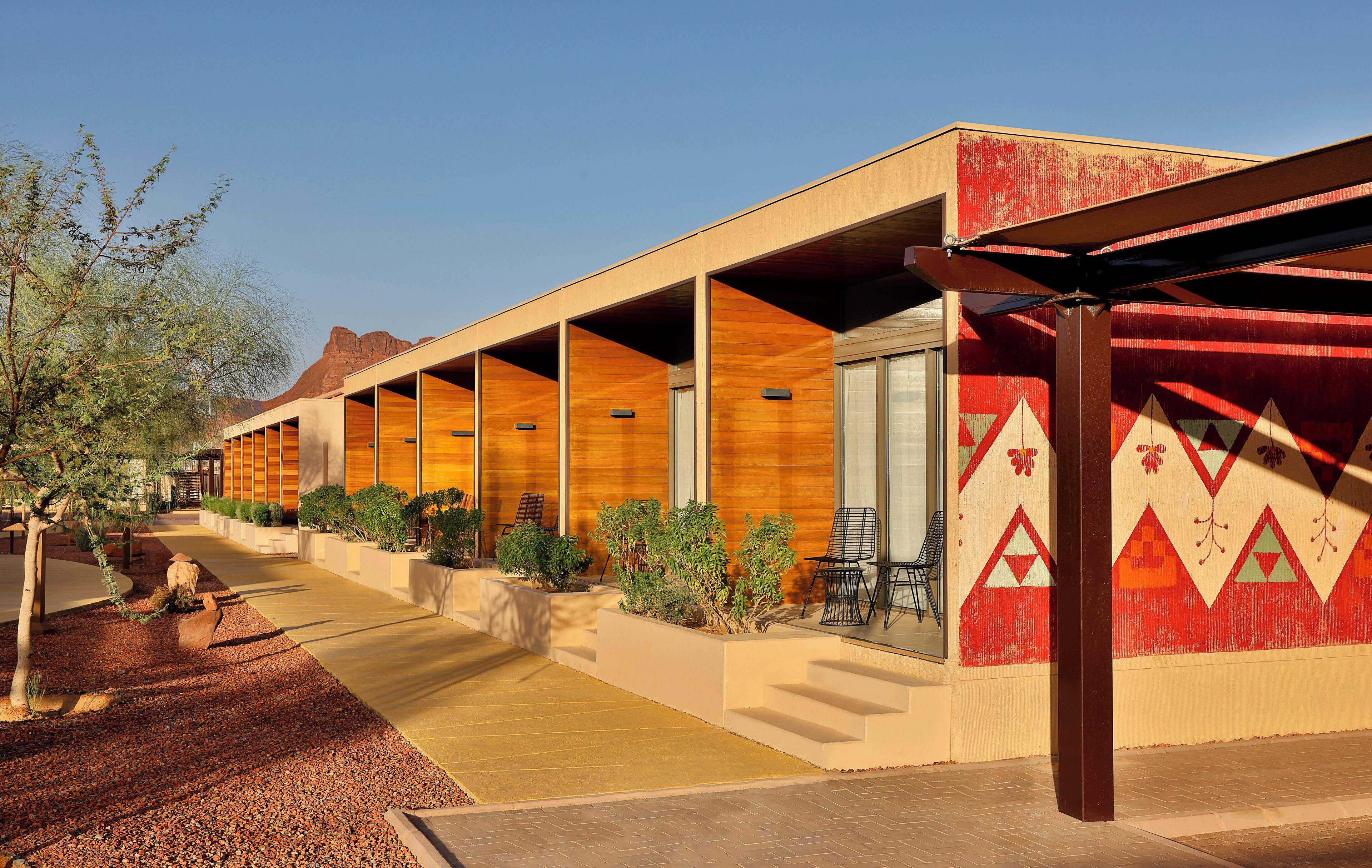 A modern hotel with a long corridor, outdoor seating, and a distinctive red and beige color scheme.