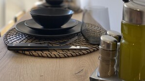 Une table à manger avec des assiettes noires, un verre et des salières et poivrières.