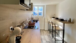 Une cuisine moderne dotée d’un plan de travail en bois, d’un four à micro-ondes encastré et d’une fenêtre laissant entrer la lumière naturelle.
