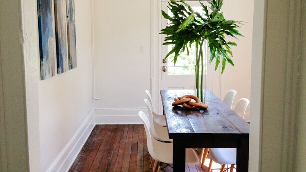 A dining area with a wooden table, white chairs, and a potted plant. - Beautiful Forsyth Park Victorian - Walk to it all! (Savannah)
