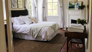 A bedroom with a bed, a fireplace, and a window with curtains. - Beautiful Forsyth Park Victorian - Walk to it all! (Savannah)