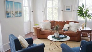 A living room with a brown sofa, two blue armchairs, a coffee table, and a potted plant. - Beautiful Forsyth Park Victorian - Walk to it all! (Savannah)
