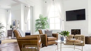 A spacious living room with leather armchairs, a round coffee table, and a large potted plant.