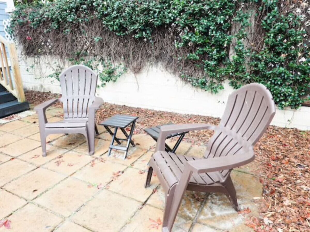 An outdoor patio with two Adirondack chairs and a small table.