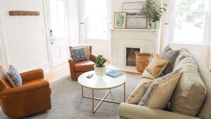 A living room with a fireplace, a sofa, a coffee table, and a side table. - Beautiful Forsyth Park Charmer - Amazing Location! (Savannah)