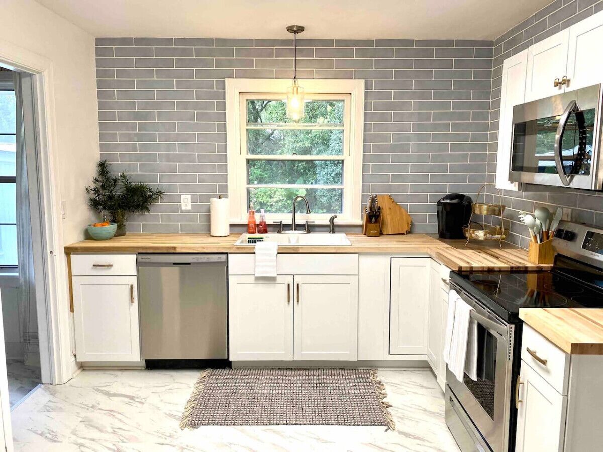 Una cucina moderna con mobili bianchi, forno integrato e microonde sopra il piano cottura.
