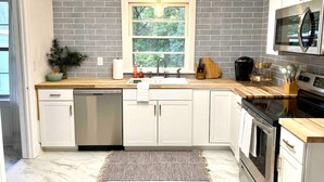A modern kitchen with white cabinets, a built-in oven, and a microwave above the stove.